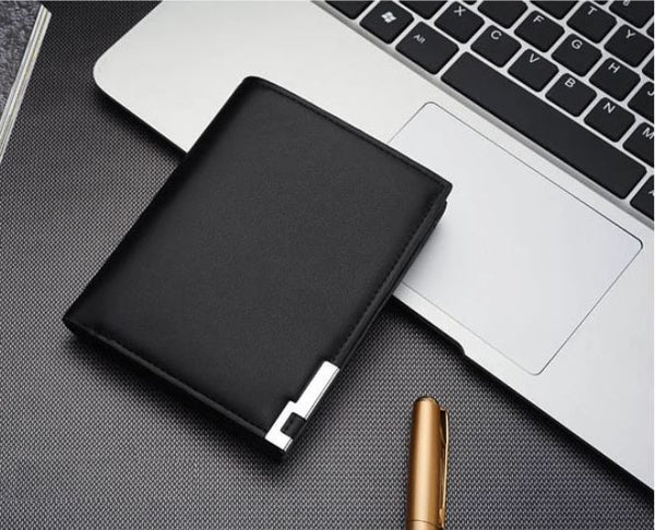 Image of men's designer leather wallet next to a macbook keyboard.