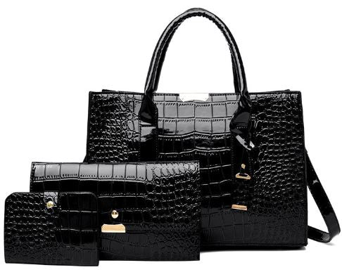 Image of a black Alligator skin tote bag, clutch, and small wallet standing side by side